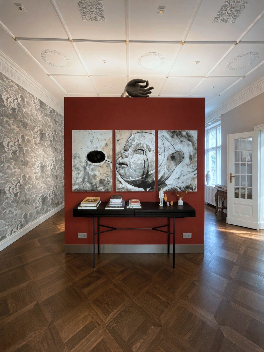 Mur rouge avec un triptyque, une sculpture de main au sommet et un papier peint à nuages