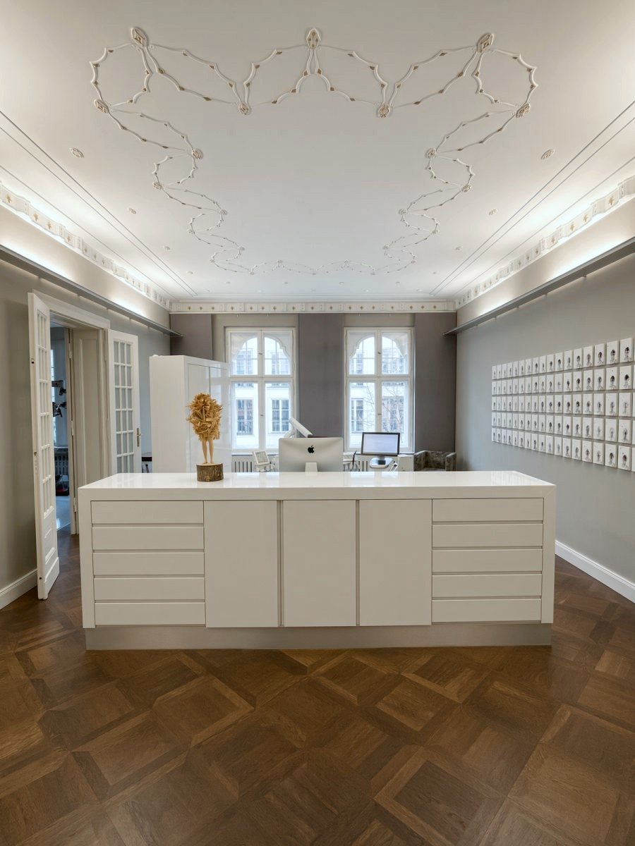 Pièce au plafond en stuc avec comptoir blanc, parquet et un mur de petits portraits